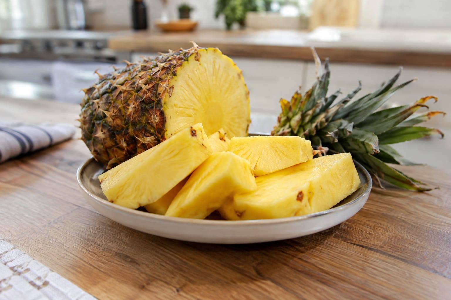 Morceaux d’ananas frais, pelés et coupés en petits dés, posés dans une coupelle sur une table claire.