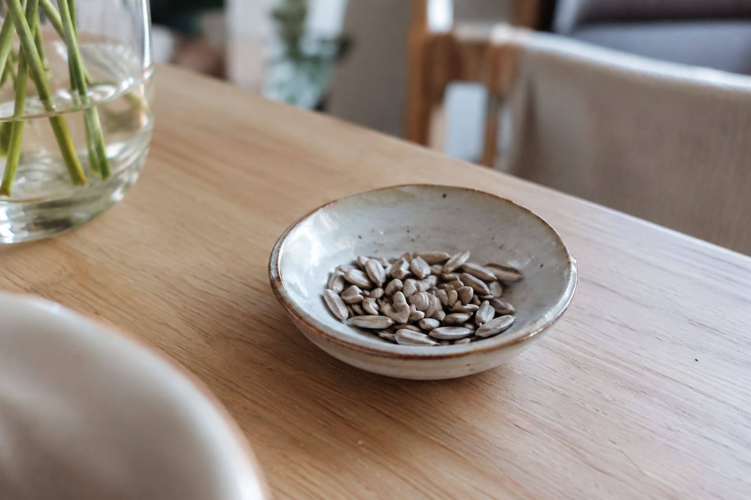 Graines de tournesol décortiquées et non salées disposées dans une petite coupelle sur une table claire.