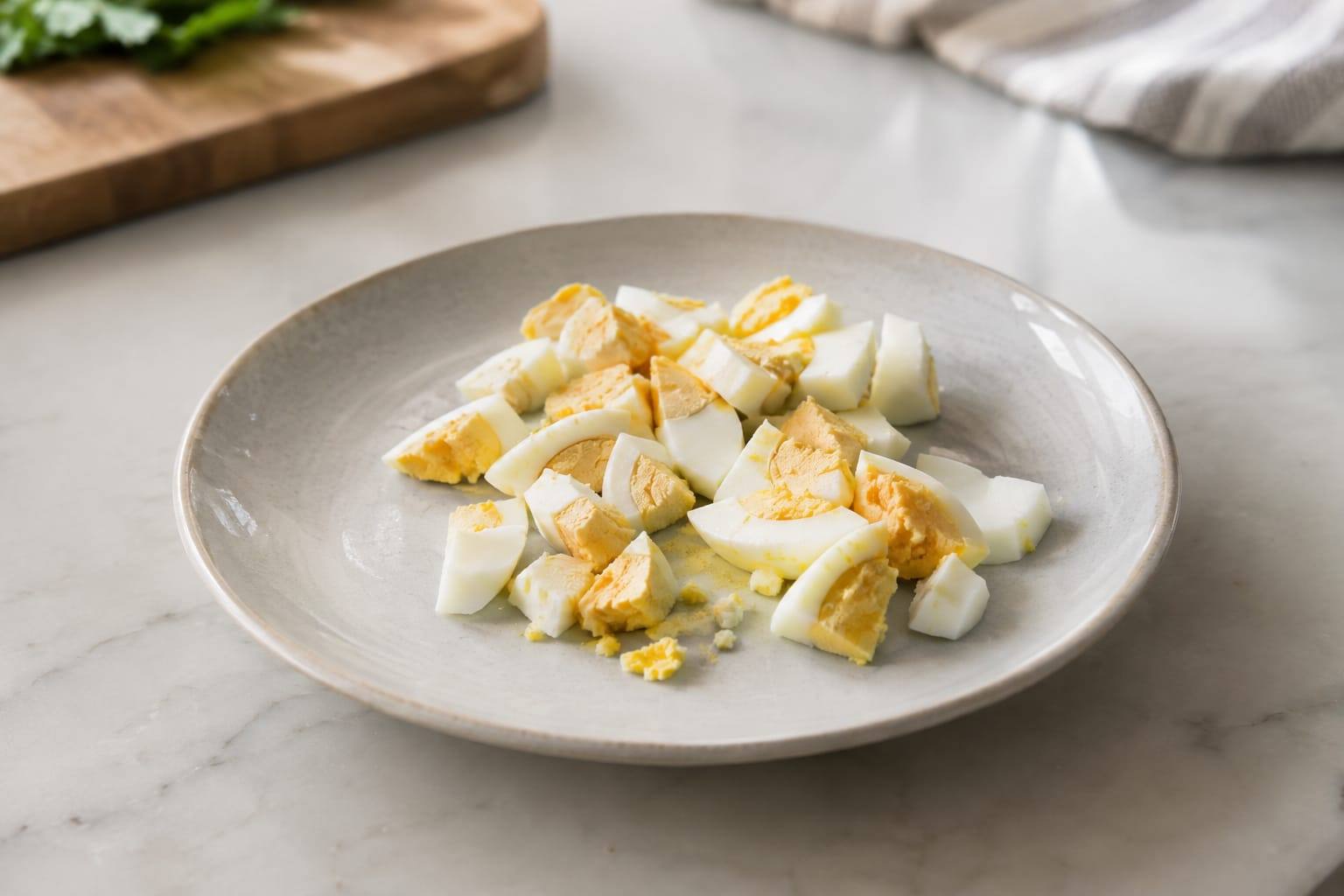 Morceaux d’œuf dur nature, refroidis et découpés en petites portions sur une assiette claire.