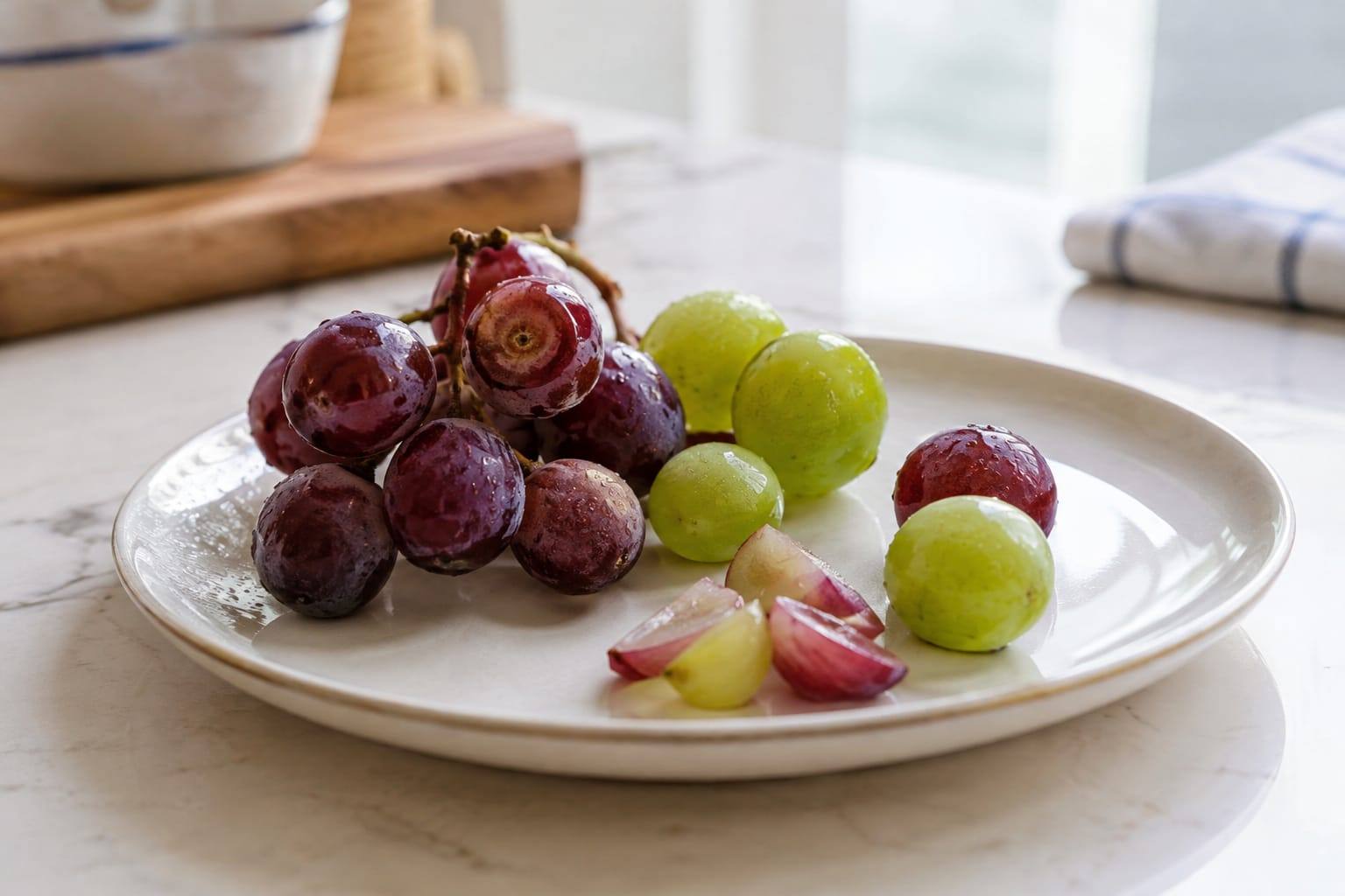 Quelques grains de raisin frais lavés, coupés en petits morceaux sur une assiette claire, sans autre aliment.