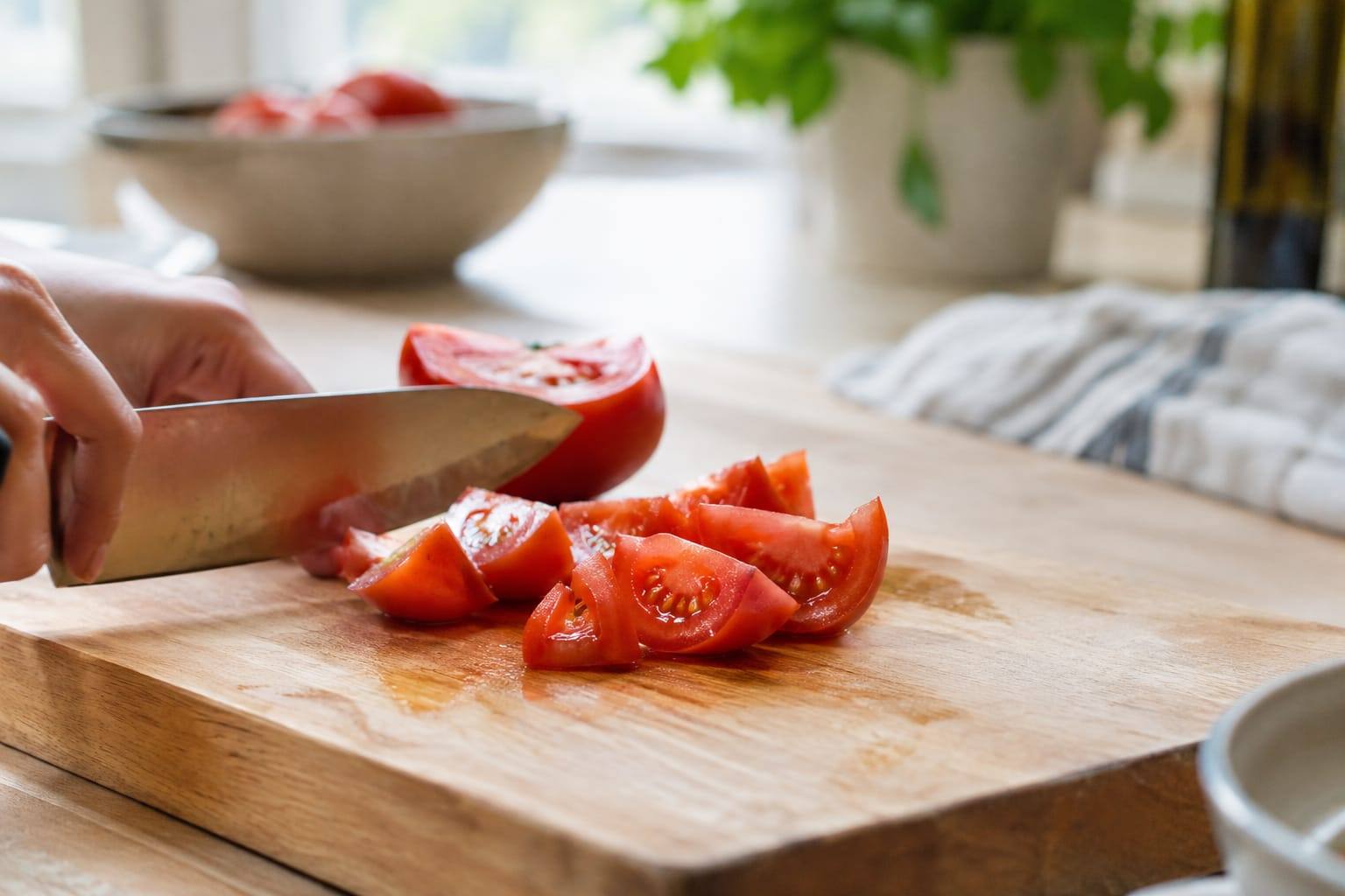 Tomate rouge bien mûre, coupée en quartiers sur une planche propre, sans feuille ni tige.